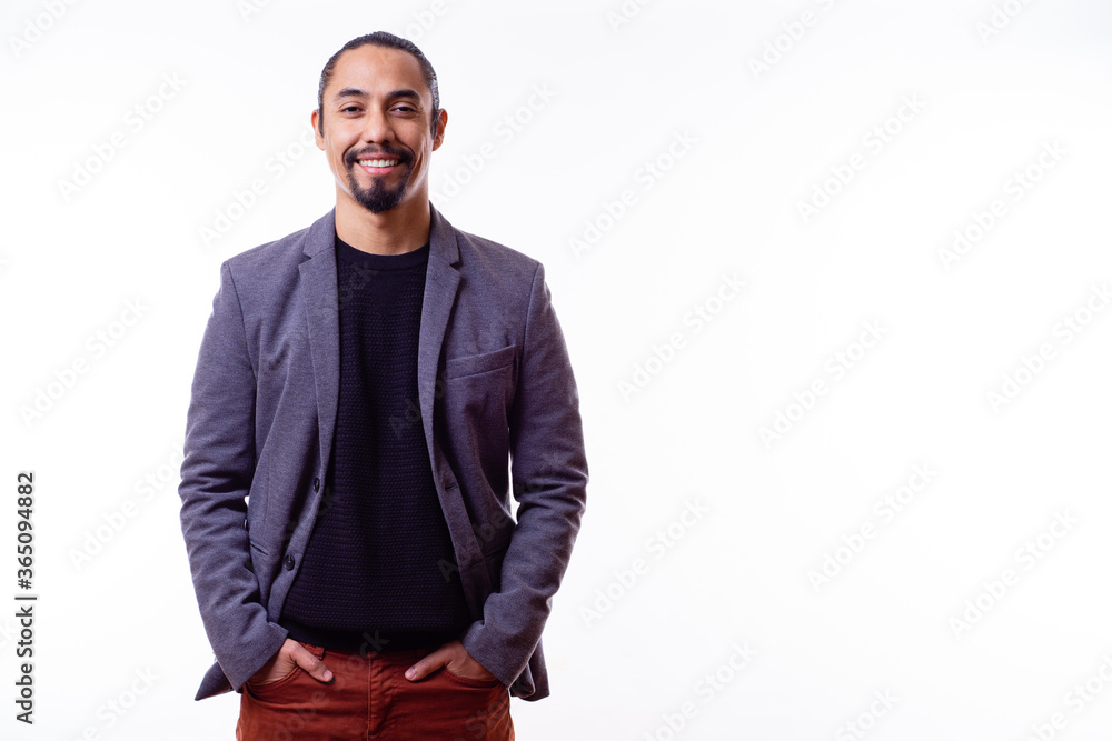 Fototapeta premium Portrait of a happy Latino businessman man on white background. Successful multiethnic man with hands in pants pockets. Young successful Latino businessman. Copy space. Business concept.