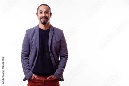 Portrait of a happy Latino businessman man on white background. Successful multiethnic man with hands in pants pockets. Young successful Latino businessman. Copy space. Business concept. photo