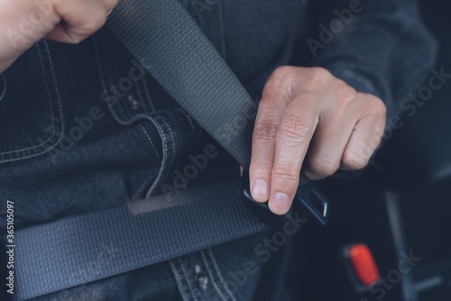 Man fastening seat belt inside a car