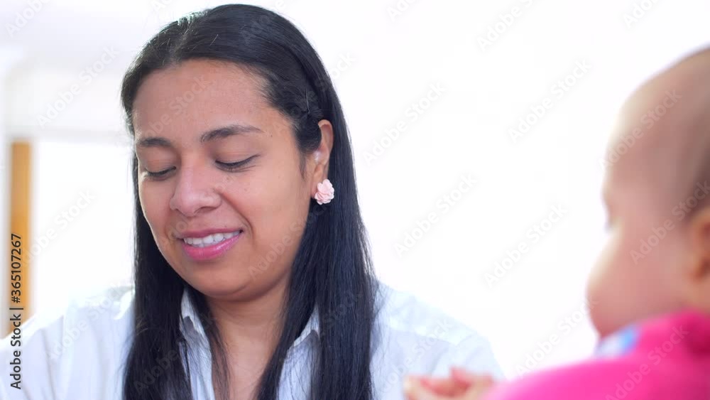 A beautiful Latin American mother feeding a baby with a spoon, close-up, white background, white and pink clothing A beautiful Latin American mother feeding a baby with a spoon, close-up, white background, white and pink clothing