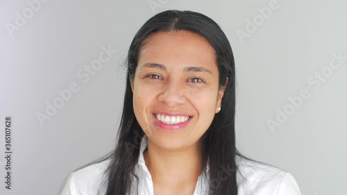 Close-up of a beautiful Latin American Hispanic young woman dressed in white, looking at camera, smiling