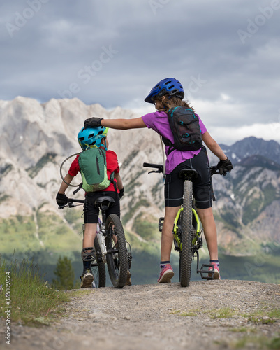 A big sister is comforting a little brother on a family mountain bike ride in Kananaskis Alberta Canada.