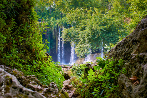 Waterfall in the rainforest, rocks and foliage in the foreground. Upper Duden waterfall in Turkey, Antalya © Om.Nom.Nom