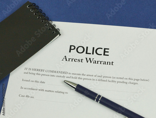 Police Arrest Warrant form with police notebook and pen. photo