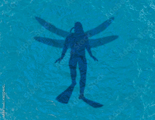 Scuba diver silhouette swimming under water in the ocean near the surface. Top vew. Human with dragonfly wings