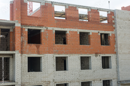 Background from the wall of a house under construction. Windows without glass. Openings. Red brick, concrete. White paint.