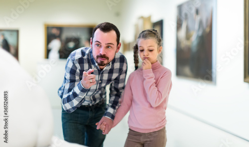 surprised father and daughter regarding paintings in halls of museum