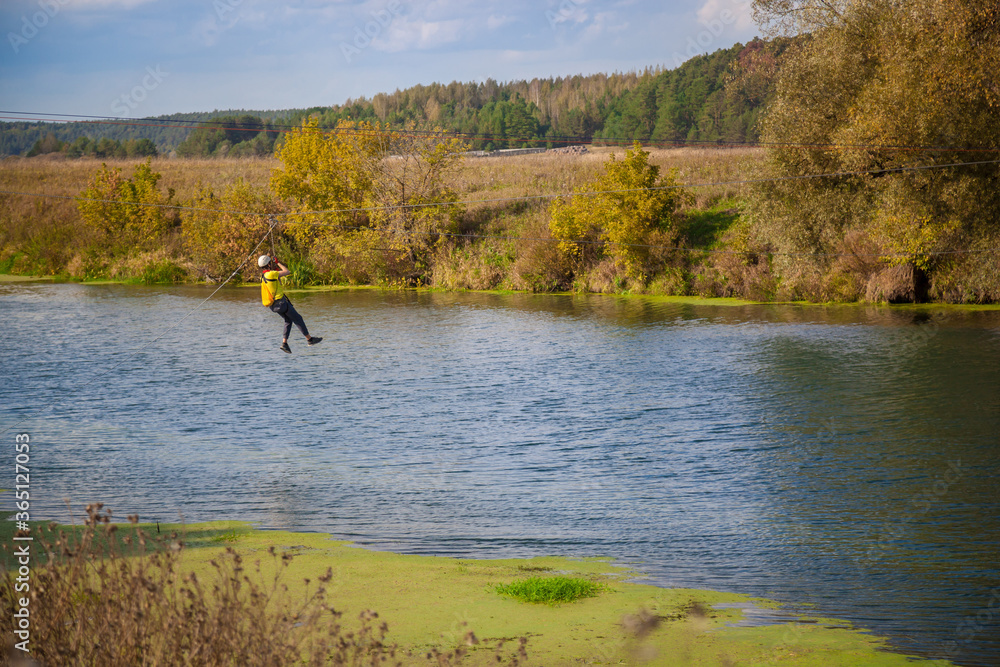 A man crosses the river on ropes stretched from shore to shore. Crossing the river. A man crosses the river on ropes stretched from shore to shore. Crossing the river.