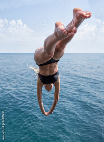 Fotografija Female person in black swimsuit plunging into deep water of the sea