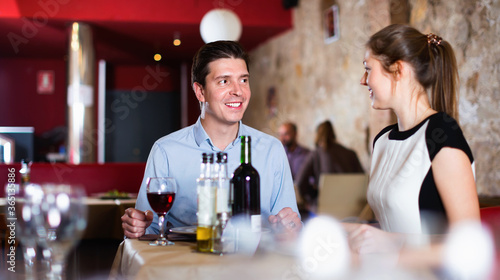 Loving happy cheerful pair enjoying evening meal and conversation at cozy restaurant