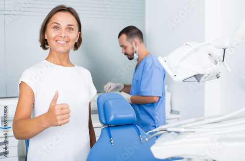 Female is standing satisfied after treatment in dental office