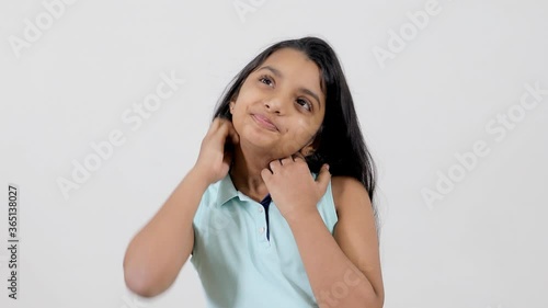 Attractive young girl in casual clothing scratching and rubbing her itchy neck. A cute little kid scrabbling rashy and dry skin around her neck during the summer season - skin issues concept photo