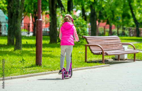 A girl rides a scooter in a city Park 