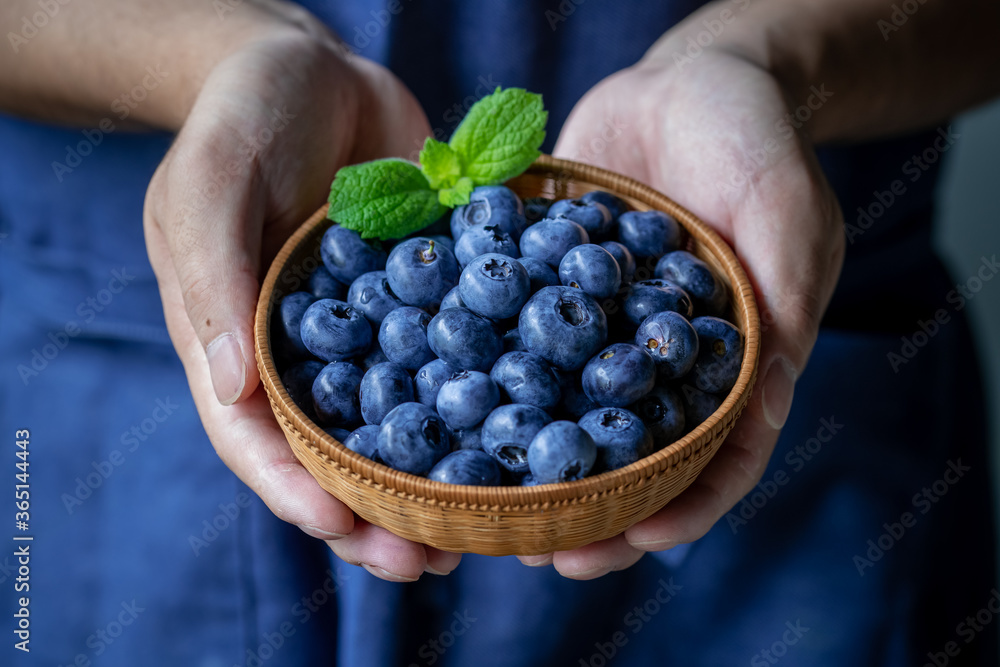 Man holds a wicker basket of blueberries.
Man holds a wicker basket of blueberries.