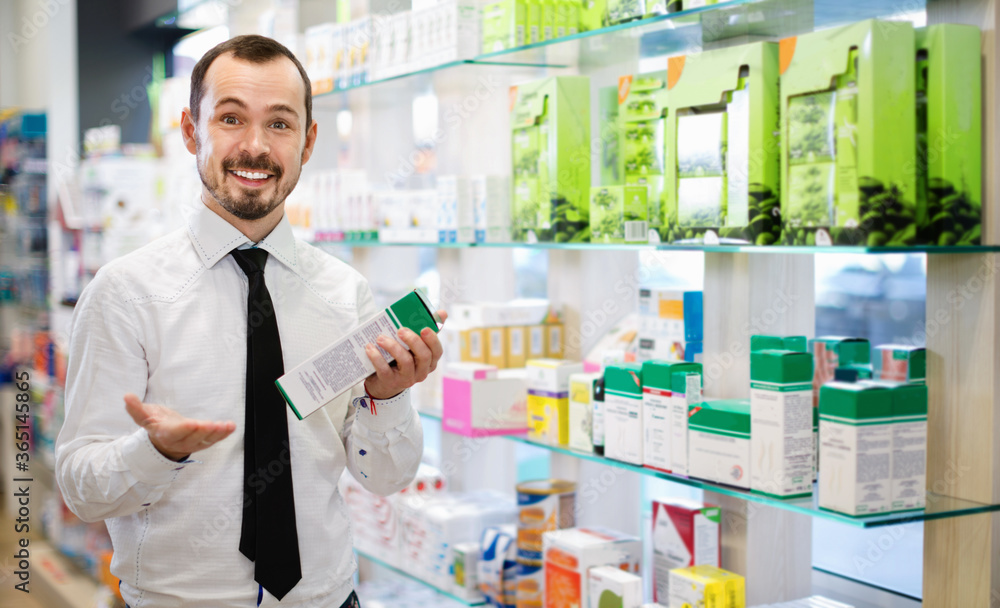 Smiling cheerful male customer looking for right medicine in pharmacy