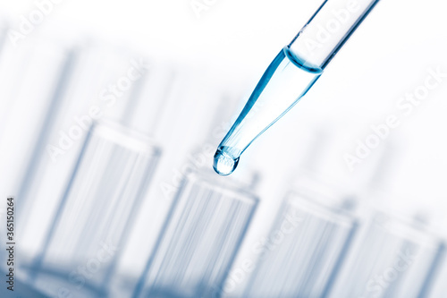 pipette with a drop and scientific laboratory test tubes in a research laboratory.