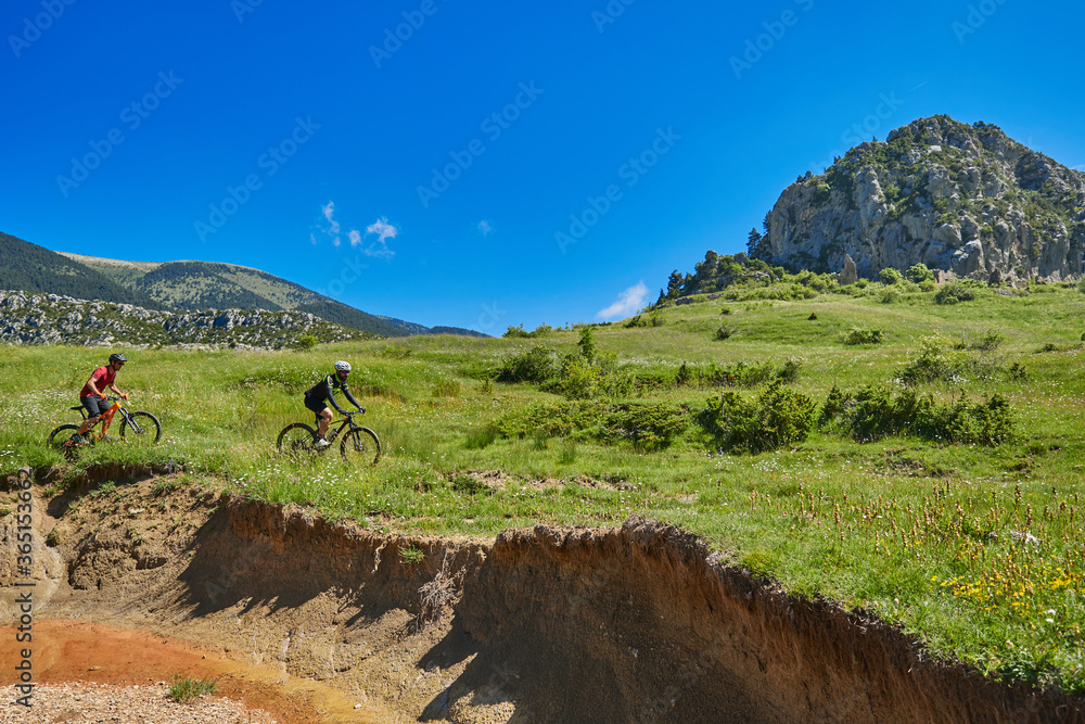 two men on mountain bikes going through idyllic mountain scenery