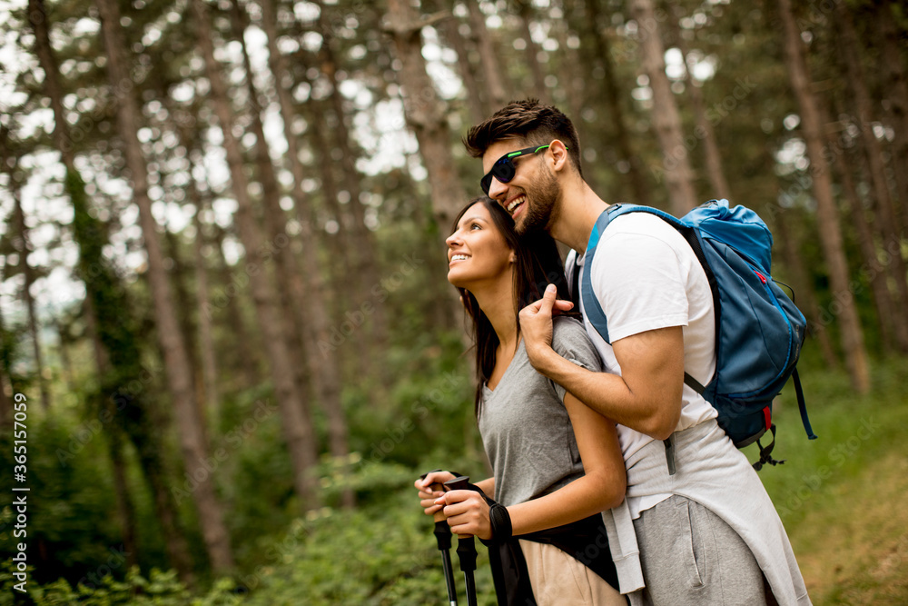 Smiling young couple walking with backpacks in the forest Smiling young couple walking with backpacks in the forest