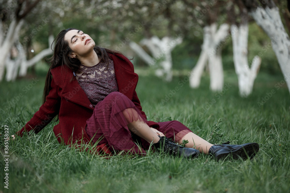 a girl in a flowery garden in a maroon coat a girl in a flowery garden in a maroon coat