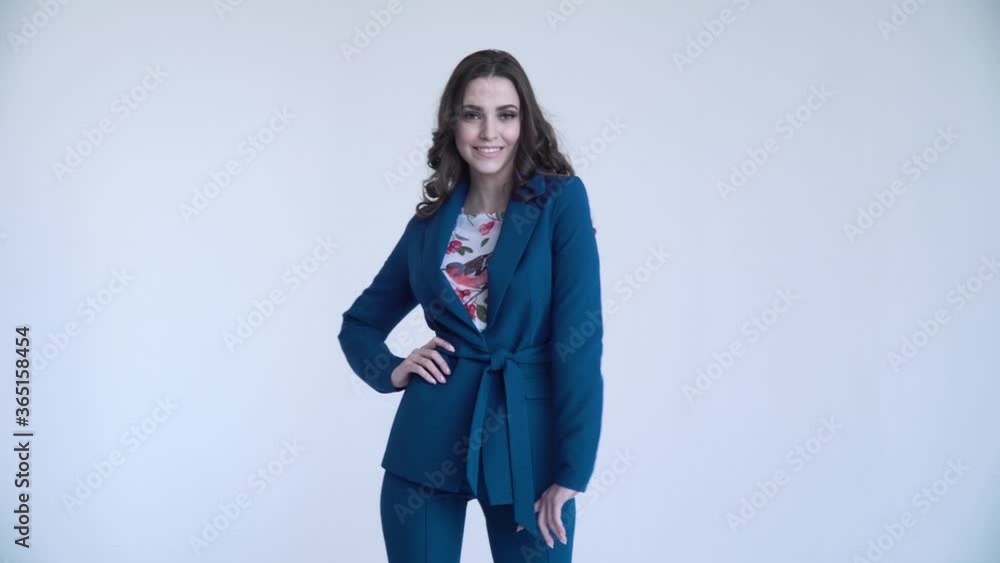 A business lady poses in a blue jacket and trousers on a white background. The sexy woman unbuttoned her jacket A business lady poses in a blue jacket and trousers on a white background. The sexy woman unbuttoned her jacket