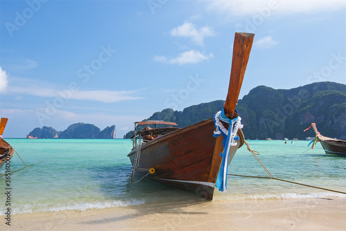 thai fishing boats on the azure sea on the bounty beach in thailand, clear sea, picturesque island, paradise enjoyment, travel and vacation, background for postcards © Aleksandr Lavrinenko