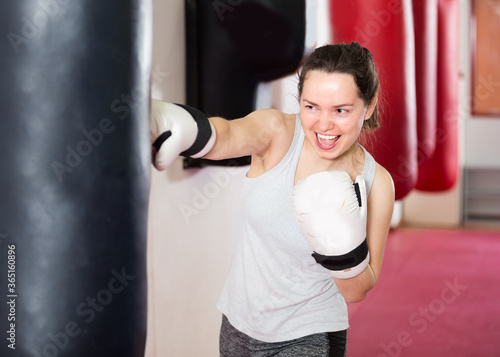 Young woman is beating a boxing bag in the boxing hall. © JackF