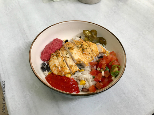 Traditional Jamaican Food Bowl with Chicken, Red Kidney Beans, Beet Sauce, Basmati Rice Pilaf, Avocado Guacamole, Jalapeno Pepper and Coconut Milk at Local Restaurant.