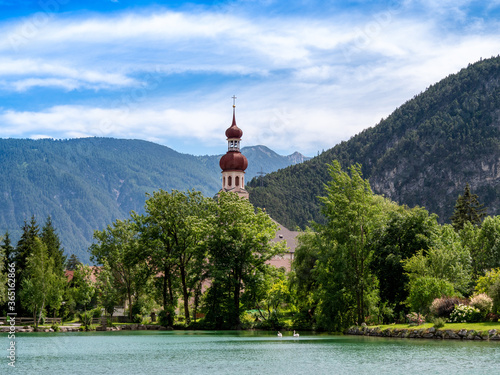 Nassereither See mit zwei Schwänen und der Kirche mit den Bergen im Hintergrund	 photo