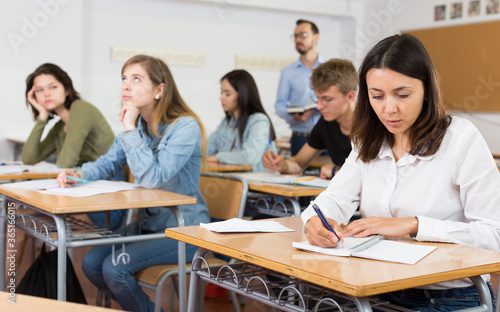 Smiling schoolgirl is learning and answering the question on paper in the class.