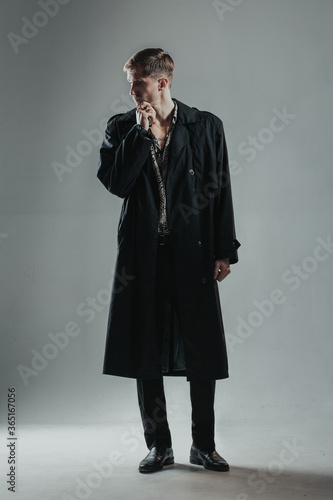 Young handsome man in black cloak looking aside with expression of thinking. Vertical image.