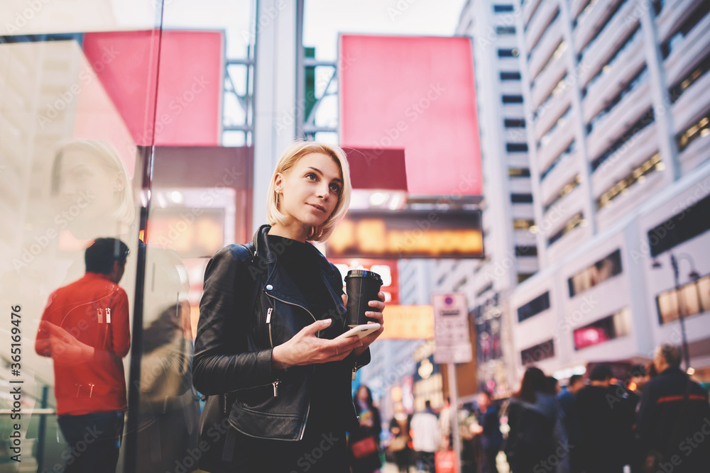 Portrait of pensive female traveler in trendy casual wear having sightseeing tour in modern business district of Chinese city feeling excited of adventures sharing photos in social networks via phone Portrait of pensive female traveler in trendy casual wear having sightseeing tour in modern business district of Chinese city feeling excited of adventures sharing photos in social networks via phone