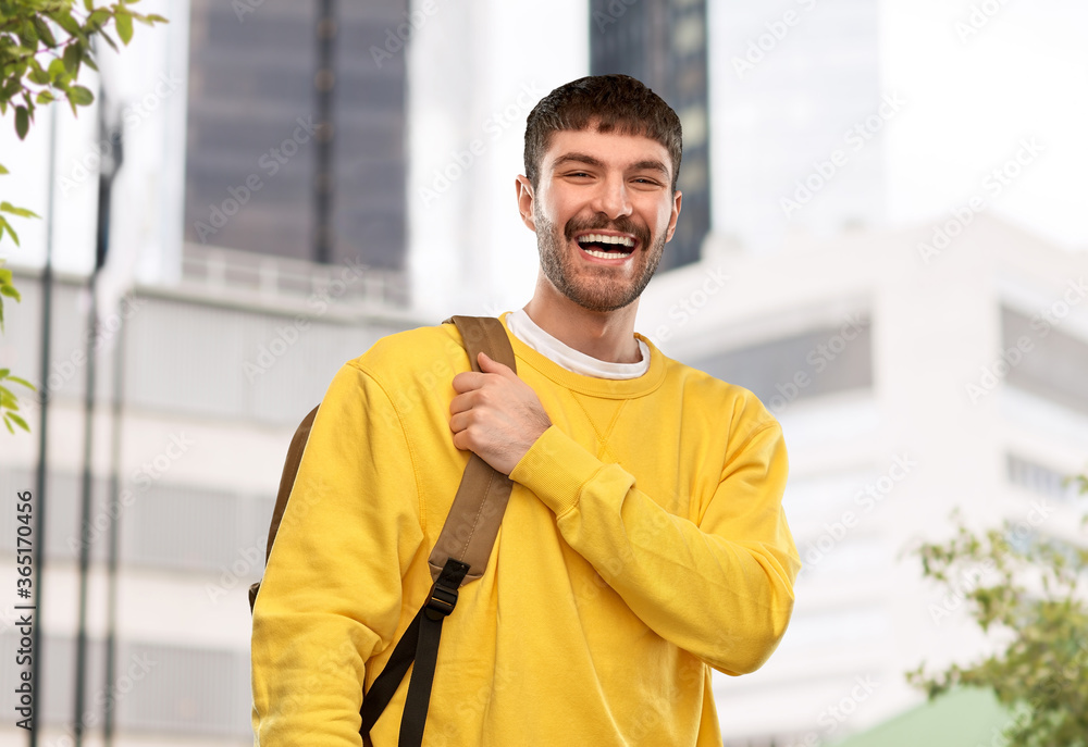 Obraz premium travel, tourism and education concept - happy smiling young man with backpack over city background