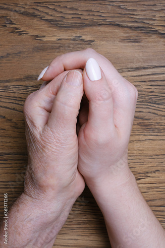 Young granddaughter hand hugging old grandmother's hand. Family and caring or aging concept