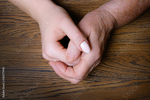 Young granddaughter hands hugging old grandmother's hands. Family and caring or aging concept