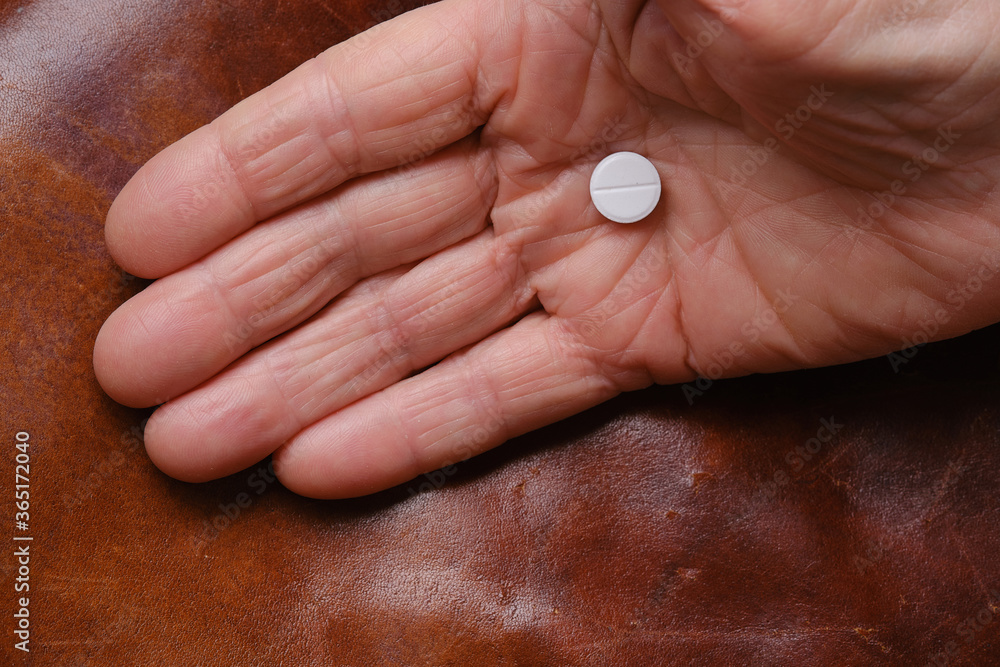 White medicine pill or tablet in hand of old woman on abstract background. Caring for the health of the elderly White medicine pill or tablet in hand of old woman on abstract background. Caring for the health of the elderly