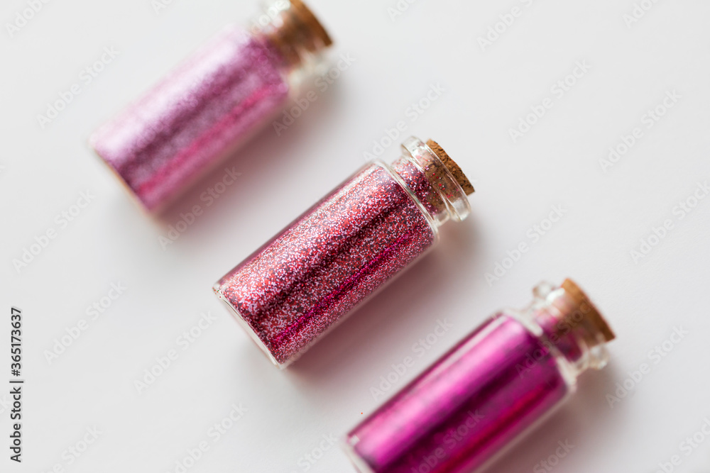 party, decoration and holidays concept - close up of glitters of different red and pink shades in small glass bottles with cork stoppers over white background party, decoration and holidays concept - close up of glitters of different red and pink shades in small glass bottles with cork stoppers over white background