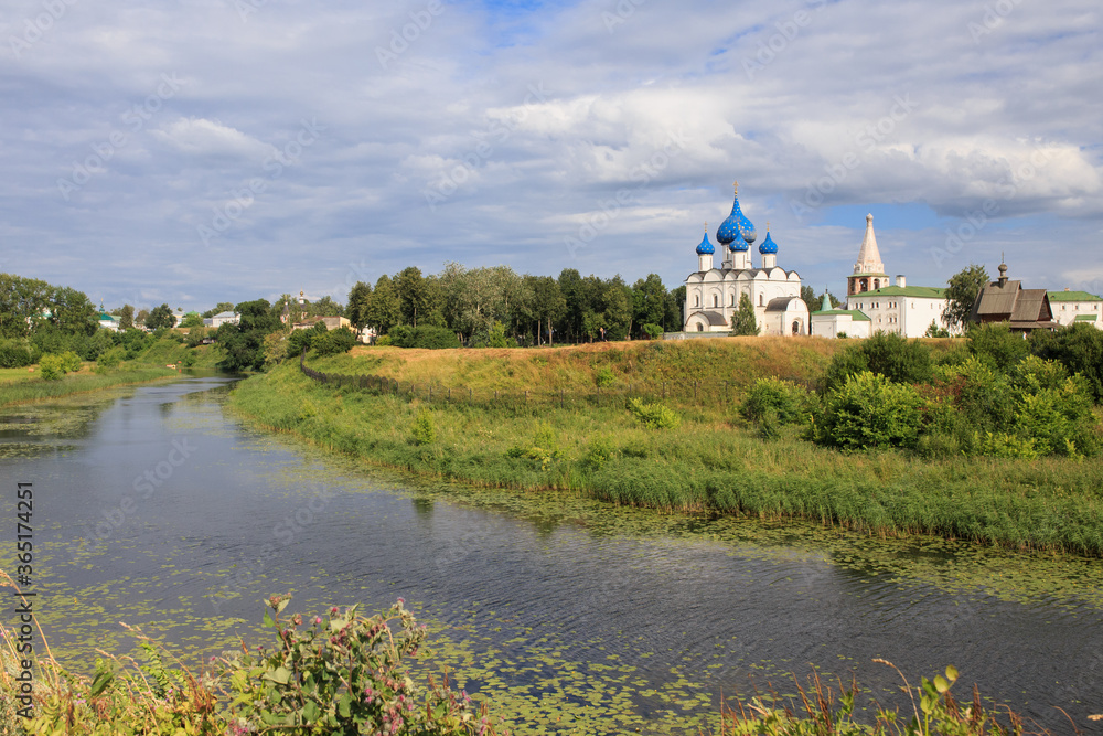 Landscape with a river and trees against the background of the Suzdal Kremlin, Russia.