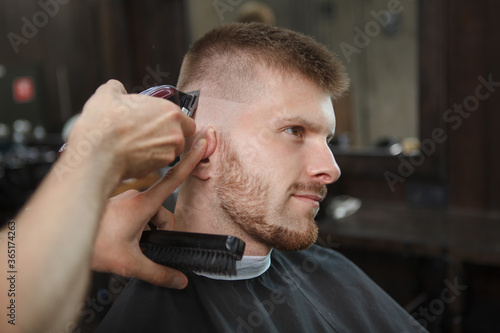 Close up of a cheerful man enjoying getting new hairstyle at the barbershop