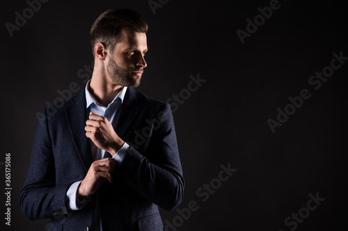 Portrait of his he nice attractive luxury perfect rich wealthy brandy trendy guy corporate executive partner mr mister fastening button copy space looking aside isolated on dark black color background photo