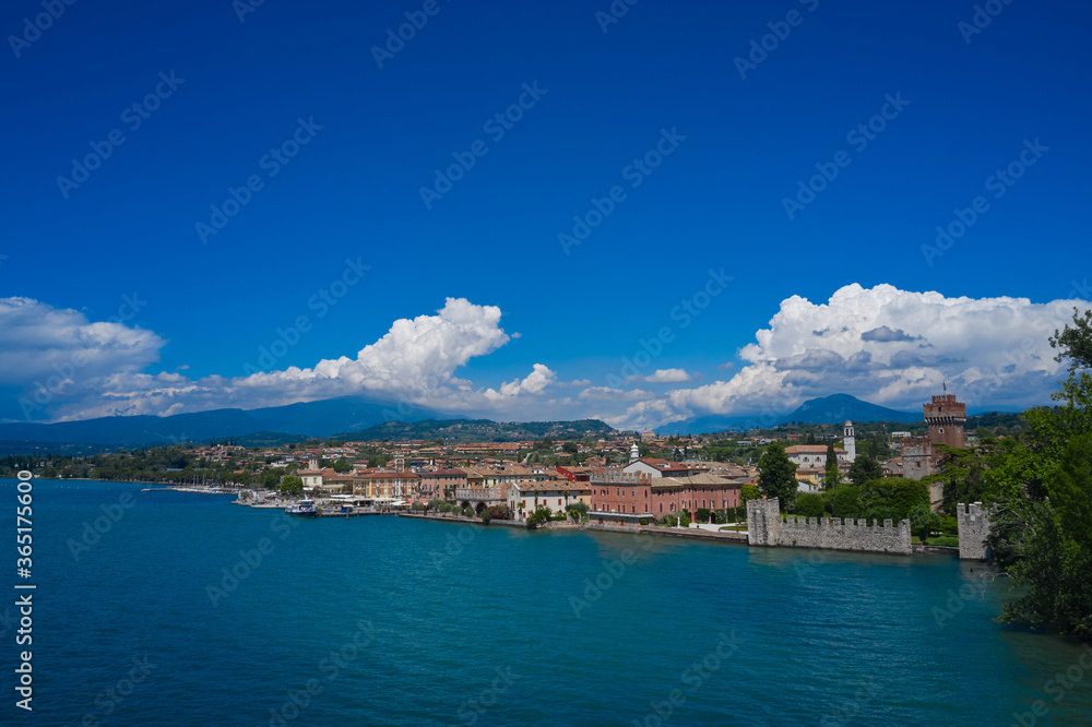 Lazise, Lake Garda, Italy. Aerial view of the historic city of Lazise, in the background cumulus clouds on a blue sky
