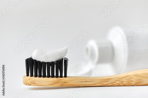 dental care, sustainability and eco living concept - close up of wooden toothbrush with white toothpaste on it photo