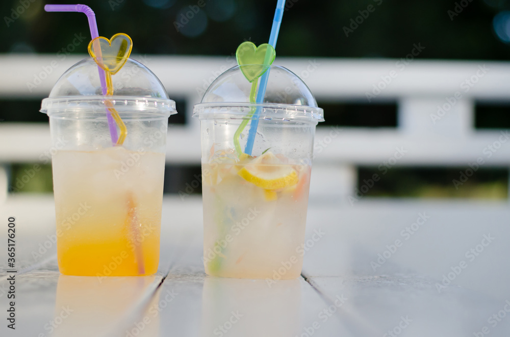 Fototapeta premium Two glasses of juice on a white wooden table. Cold drinks. Orange juice and mojito.