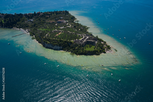 Sirmione island aerial view. Archaeological site of Grotte di Catullo. Garda lake, Sirmione, Italy. Aerial view on Grotte di Catullo. Sun reflections in water