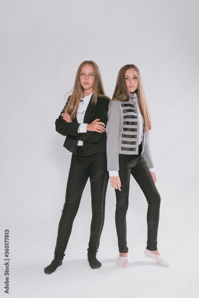 Fototapeta premium Two cute girls schoolgirls in a trendy school uniform on a white background. School fashion. Children's school fashion clothes