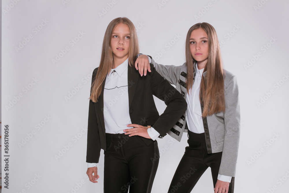 Two cute girls schoolgirls in a trendy school uniform on a white