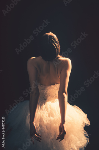 Young beautiful ballet dancer is posing in studio, view back.