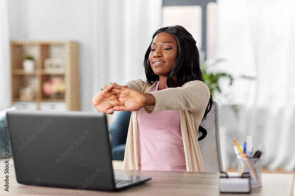 remote job, e-learning and people concept - happy smiling young african american woman with laptop computer stretching at home office remote job, e-learning and people concept - happy smiling young african american woman with laptop computer stretching at home office