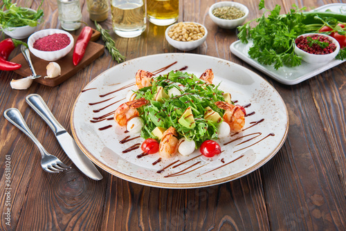 Fresh healthy avocado and shrimps salad with arugula  tomatos and mozzarella cheese on wooden background  cooking concept with ingredients