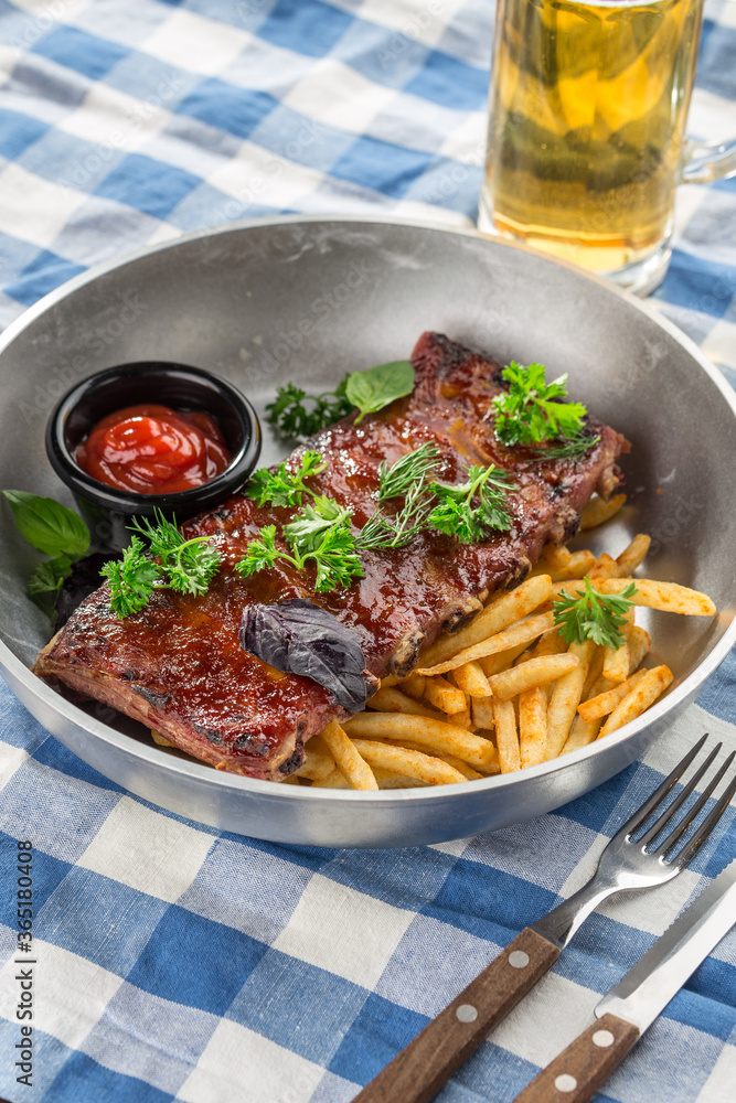 grilled pork ribs with french fries and glass of beer on fabric napkin grilled pork ribs with french fries and glass of beer on fabric napkin