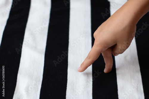 A man made of fingers walks along a black and white striped road. Crosswalk. Concept photo of black and white stripes in life